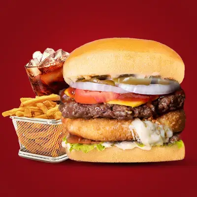 a large burger with a glass of soda and fries